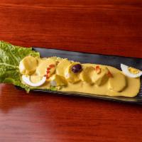 Papa a la Huancaina · Sliced baked potatoes topped with yellow Peruvian cheese cream sauce. 