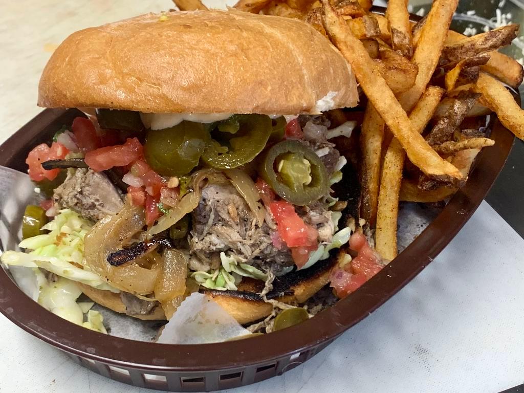 Carnitas (Pork) Sandwich · Marinated and slow-roasted pork served over slaw with caramelized onion, roasted poblano, Texisauce, poblano mayo, and red onion escabeche.