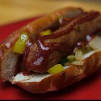 Urban Sausage · Plant based sausage severed on pretzel bun topped with peppers onions & dill pickles, and si...