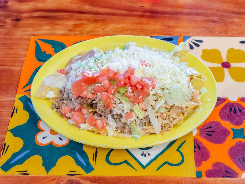 Nachos Toro · Cheese nachos with ground beef, shredded chicken and beans all topped with lettuce, tomatoes and sour cream.