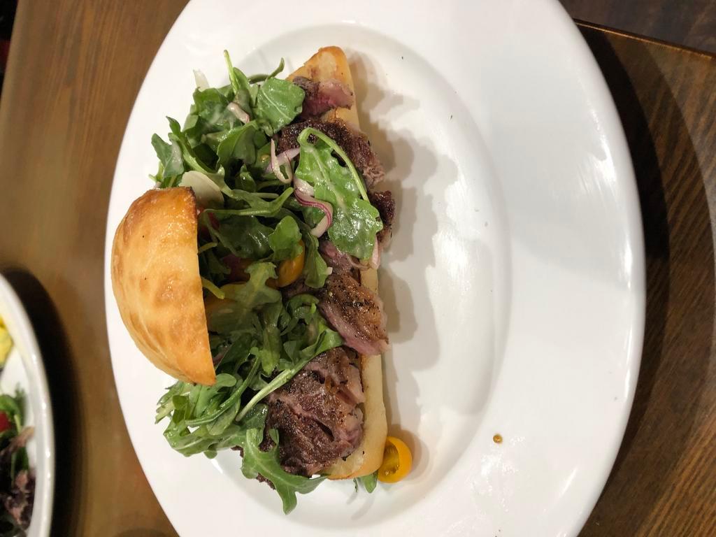 New York Open Face Steak Sandwich · Angus steak seasoned with lemon and rosemary, arugula, cherry tomatoes, onions and Parmesan cheese on panini bread.