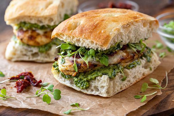 Creamy Grill Chicken  Genovese with Homemade Pesto · This grilled chicken sandwich with pesto is our  delicious take on a gourmet, bistro-inspired favorite. Your choice of roll or bread is slathered in our easy homemade pesto sauce, then topped with juicy grilled chicken breast, melted smoked mozzarella cheese, sun-dried tomatoes and fresh arugula greens for lots of bright, bold flavor! Grilled chicken cutlet, mozzarella, sun-dried tomato, arugula, roasted peppers and pesto sauce.