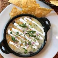 Black Bean Dip (& Chips) · A black bean purée topped with aged cheddar, cream, cilantro and onion