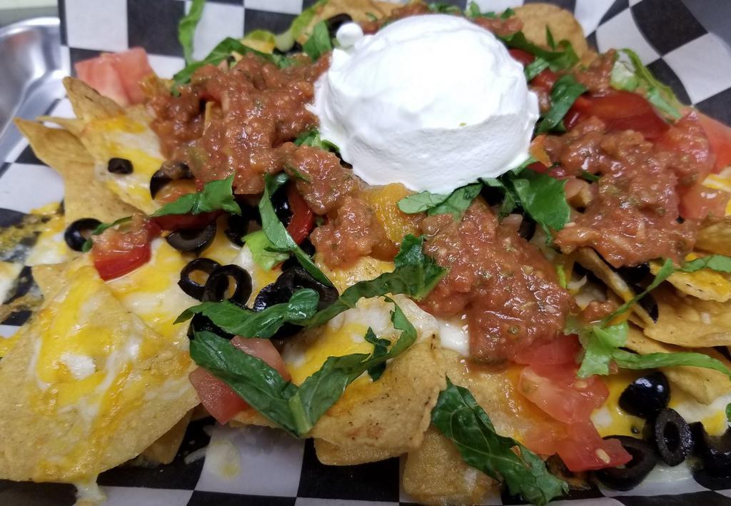 Pan Nachos · A mound of fresh fried corn tortilla chips topped with cheddar jack cheese, diced tomatoes, black olives, shredded lettuce and cherry peppers served in a pan with salsa and sour cream 