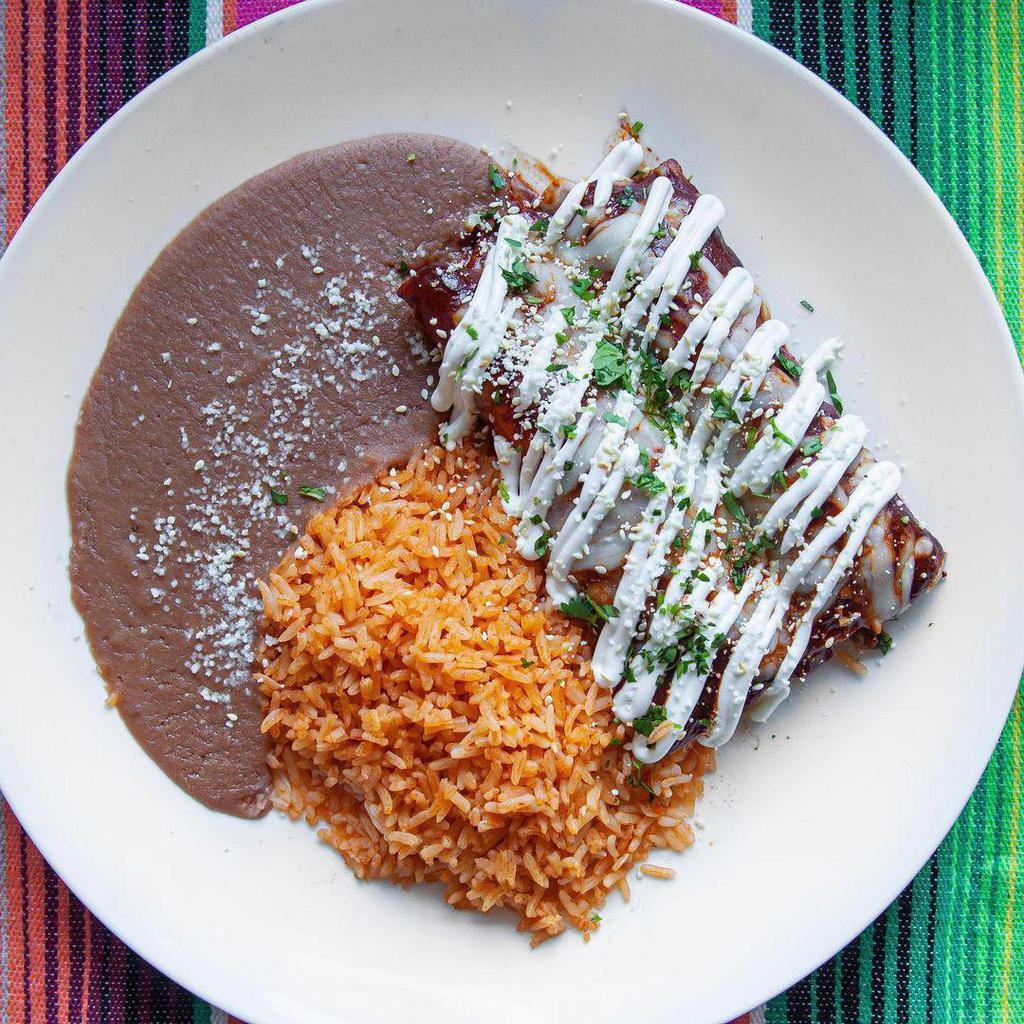 Enchiladas Rojas · Stuffed rolled corn tortillas covered in our house mole, served with tomato rice, refried beans, Cotija cheese, crema, sesame seeds, cilantro, chicken.