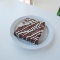Triple Chocolate Brownie · Chocolate brownie square with chocolate chips and white chocolate drizzle.