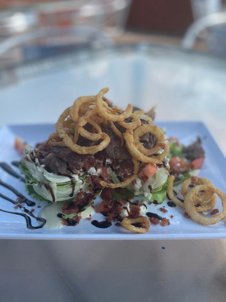 Steak Salad · Iceberg wedge, steak, blue cheese crumbles, bacon, tomato, crispy onions topped with blue cheese dressing and balsamic glaze. 