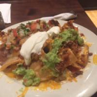 Super Nachos · refried beans, pico de gallo, sour cream, guacamole cheese. Choice of meat or Veggie.