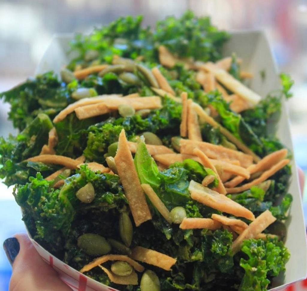 Kale Salad (GF) · Our massaged kale salad, dressing with cheezy chipotle-lime dressing and topped with crunchy roasted pepitas and crispy in-house fried tortilla strips. Gluten free.