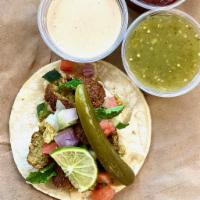 Vegan Falafel Taco · Double corn tortilla, Hummus spread, falafel ball, pico de Gallo, pickled cucumber, vegan Ta...