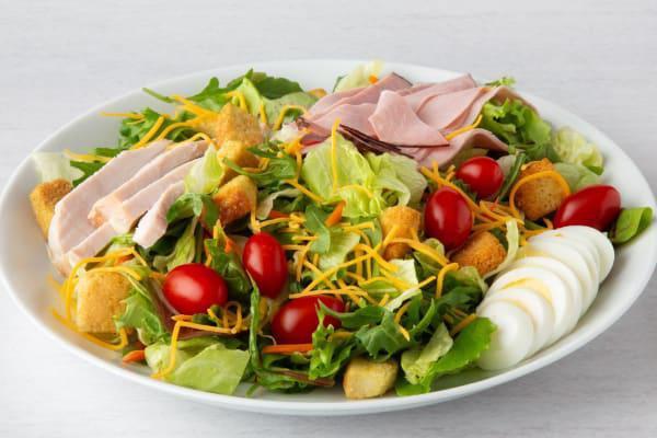 Celebrity Chef Salad · Hand-carved turkey breast, ham, Cheddar/Monterey Jack cheeses, tomato, hard-boiled egg, and seasoned croutons on mixed greens.