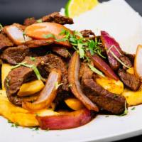 Peruvian Lomo Salteado · Chunks of sirloin, red onion, tomato slices, and served over french fries and accompanied wi...