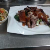 Thai Crispy Duck · Bone-in roast duck on a bed of sauteed mixed vegetables and pineapple fried rice on the side.