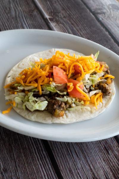 Ground Beef Taco · Loaded with fried potatoes, cheddar cheese, diced onions, green chiles, lettuce, and diced tomatoes in a flour tortilla.