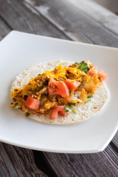 Breakfast Taco · Scrambled eggs, bacon, onions, hash browns, tomatoes, cheddar cheese, and fresh cilantro in a flour tortilla.