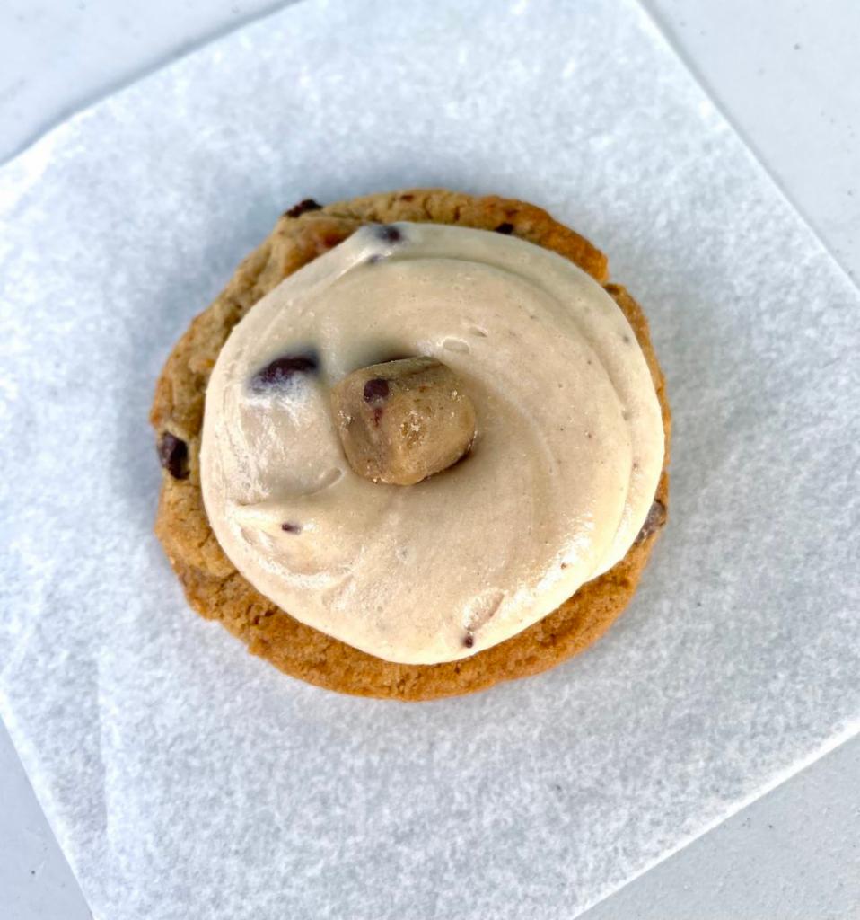 Frosted Cookie Dough Cookie · Large chocolate chip cookie with chocolate chip cookie dough frosting topped with a cookie dough bite! Each frosted cookie dough cookie will come in a cute box! 