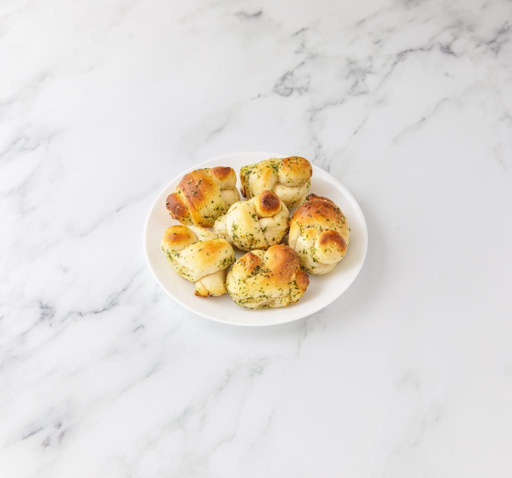Garlic Knots · A classic snack, our garlic knots are strips of pizza dough tied in a knot, baked, and then topped with melted butter, garlic, and parsley