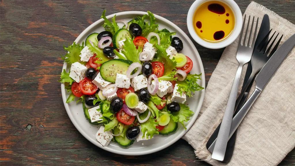 The Greek Salad · Crunchy romaine lettuce, red onions, cucumbers, tomatoes, black olives, and feta cheese with a side of lemon-olive oil dressing.