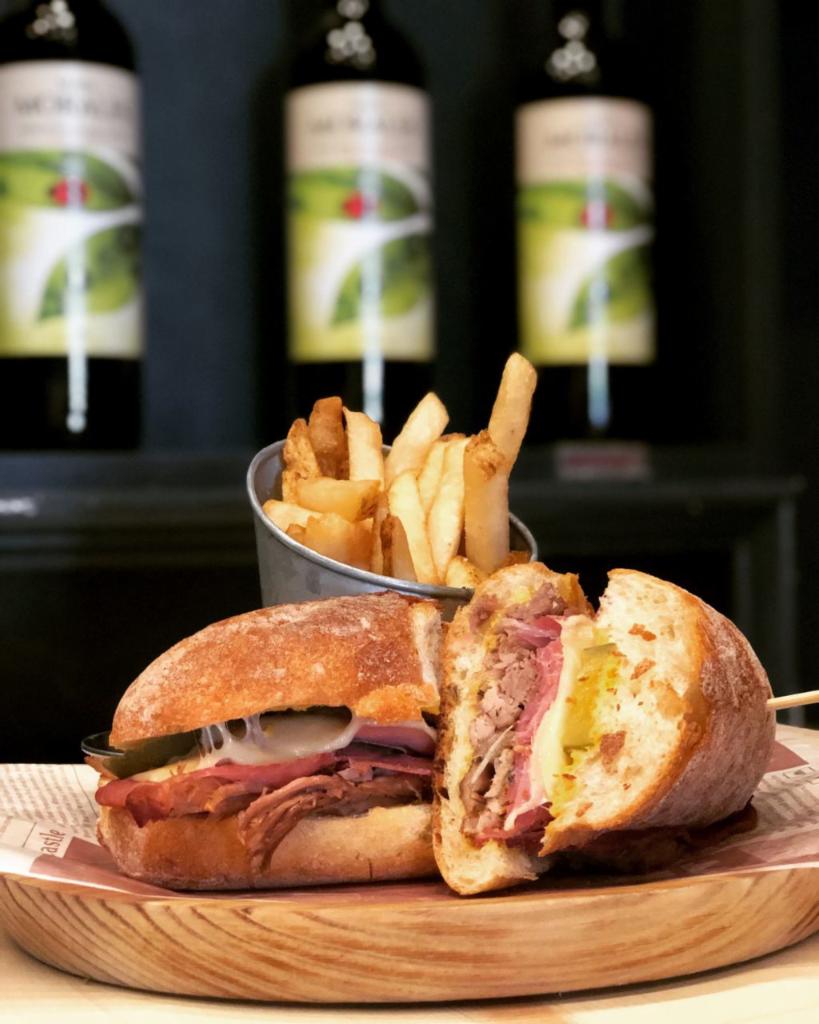 The Cuban Panini · Cuban Style Slow Roasted pork , Black forest virginia ham, Swiss Gruyere cheese, bread and butter pickles, dijon mustard garlic scented bread and Yucca Fries.