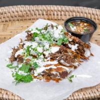 3 Birria Tacos with Consome · Top with crema, cilantro, onions, and cheese.