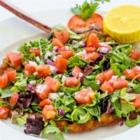 Costoletta Milanese · Thin breaded veal chop, topped with arugula, tomato and onions.