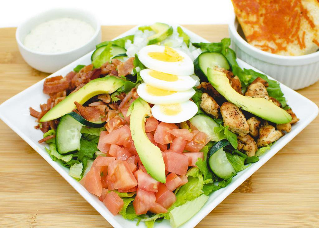 Cobb Salad · Tender grilled chicken, hard-boiled egg, crispy bacon, tomato, avocado, onions, bleu cheese, on a bed of romaine lettuce. Served with a side of buttery, cheesy garlic bread.