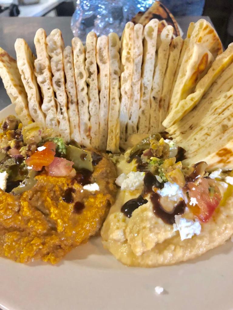 Hummus Envy · 2 flavors of hummus with soft pita topped with olives, goat cheese, peppers, pico, pesto and balsamic reduction. choose a backup flavor in case we are out of your first choice