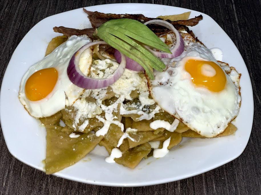Breakfast Chilaquiles Verdes · Fried tortilla strips simmered in red or green salsa. Served with cojita cheese, sour cream, avocado, onions and two eggs any style.