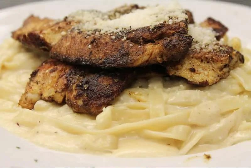Cajun Fettucini Alfredo · Delicate fettucini in a creamy parmigiano sauce with blackened chicken. Served with a side of garlic bread.
