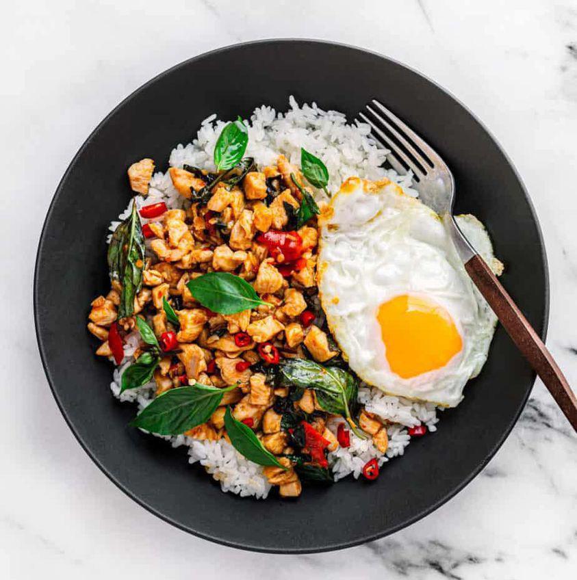Thai Chicken Basil · Chicken, diced red pepper, fresh basil with a fried egg, black pepper sprinkled on top and a side of white rice. Dairy-free. Make it halal for an additional charge.