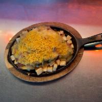 Tamale Skillet · 2 eggs on tamales over skillet potatoes, smothered with green chili and shredded cheese.