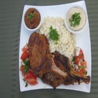 Pork Chops Plate · Grilled pork chops marinated in special spices served with rice, salad, hummus, and pita bre...