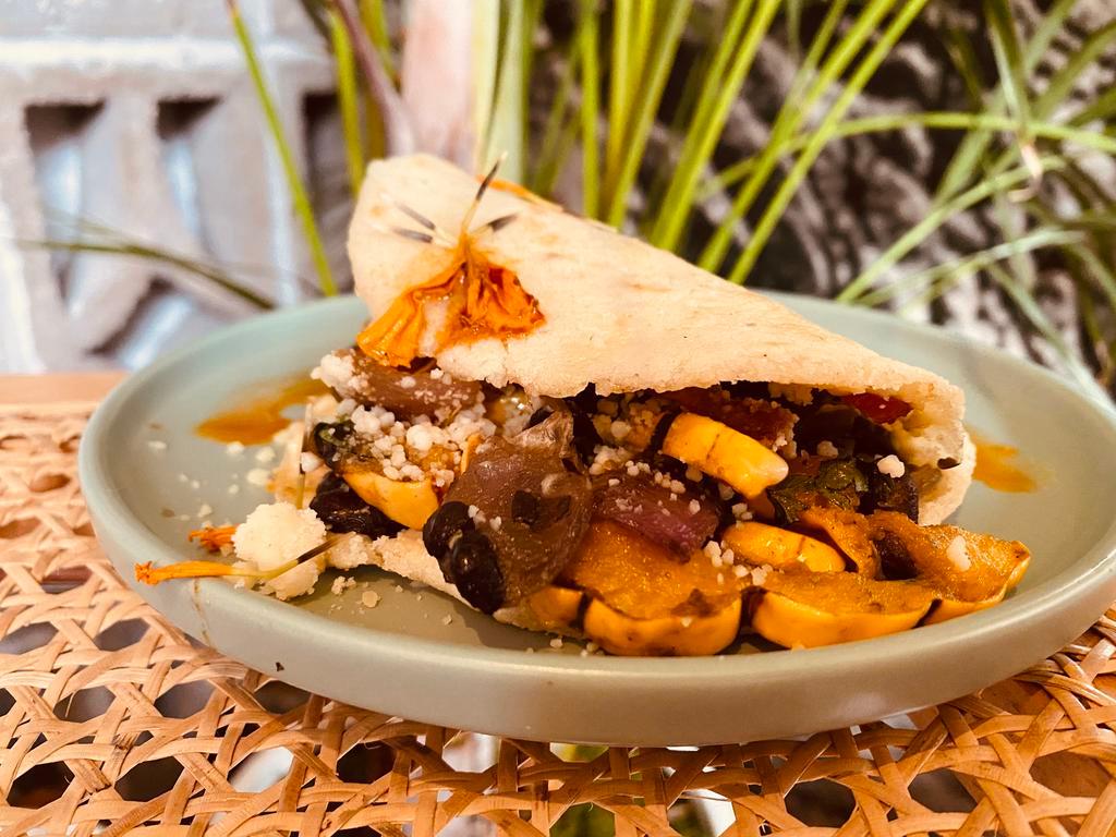Arepa Vegetariana · Made with maize and plantain. Served with black beans, roasted red onions, roasted delicata squash, chile oil, garlic aioli, butter lettuce, cotija cheese, and cilantro. Side of pina salsa. A