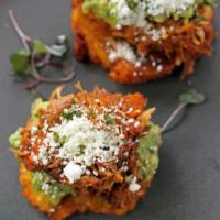 Los Maduros con Carne · Two fried ripe plantains topped with cochinita, guacamole, and cotija cheese. Drizzled with ...