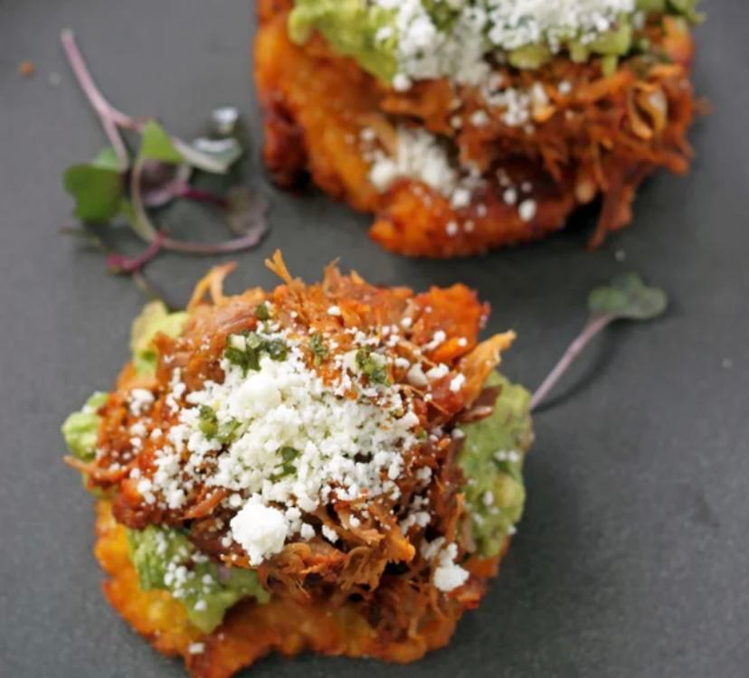 Los Maduros con Carne · Two fried ripe plantains topped with cochinita, guacamole, and cotija cheese. Drizzled with chimichurri on top. 

