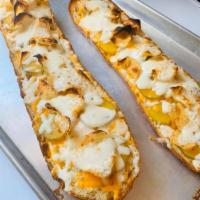 Chip and Pickles Bread Pizza · White garlic sauce, kettle chips, dill pickles, mozzarella, and cheddar cheese.