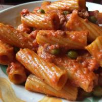 Rigatoni  · Served In a red, crumbled sausage ragú. Topped with green peas.