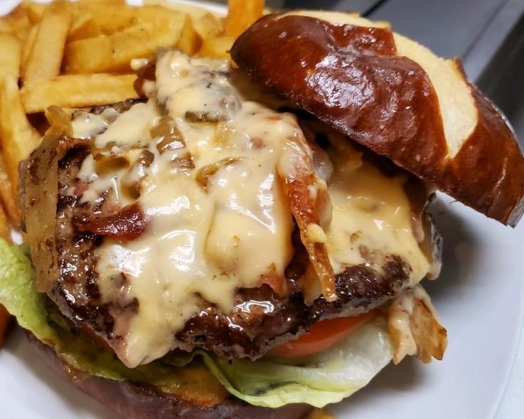 Pretzel Pub Burger · 1/2 lb Burger with bacon, lettuce, tomato & caramelized onions, topped with our delicious beer cheese and served with fries.   