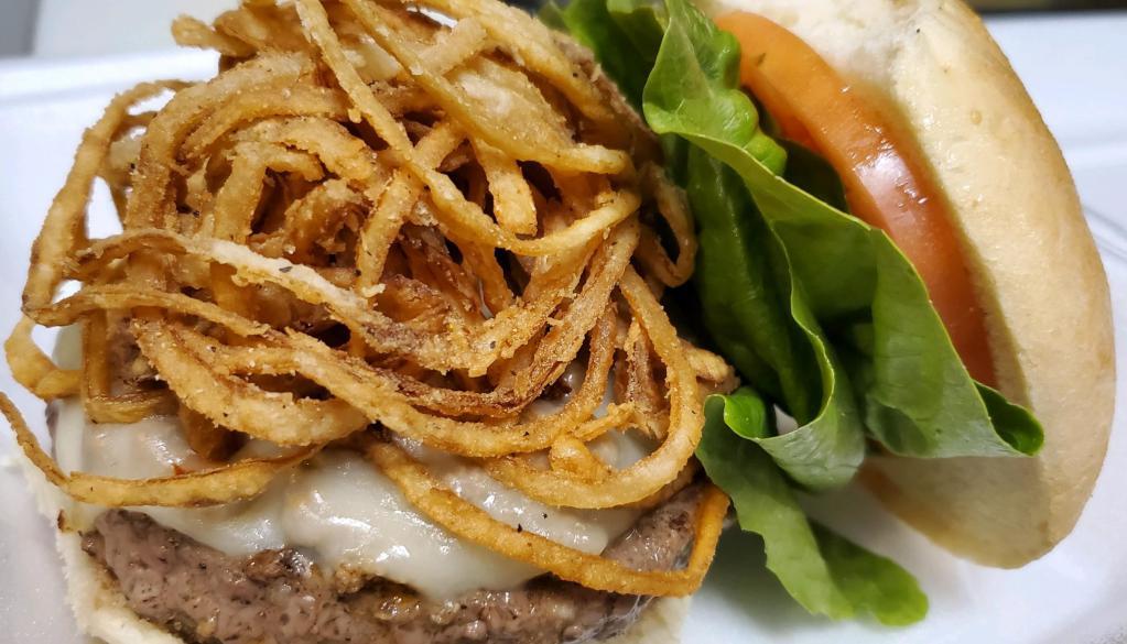 Crackin' KO Burger · 1/2 lb. burger topped with pepper jack cheese, piled high with onion straws and famous meat hot sauce. Dressed with lettuce, tomato and onion and served with fries. Spicy.