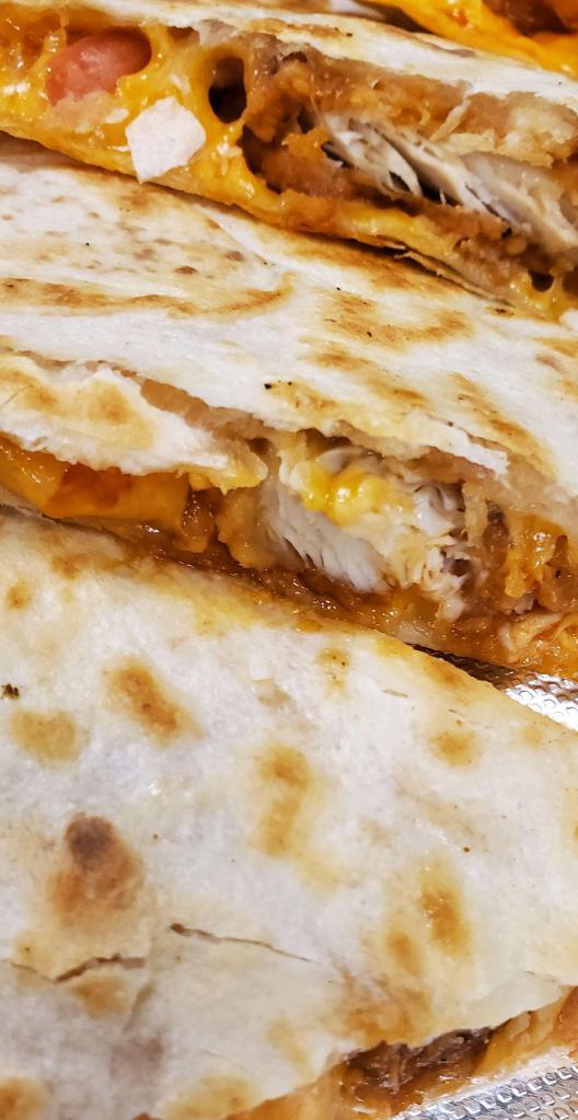 Buffalo Chicken Wing Quesadilla · Grilled flour tortillas filled with melted cheddar cheese, diced tomatoes, crumbly bleu and fried chicken tossed in mild or hot wing sauce. Served with bleu cheese.
