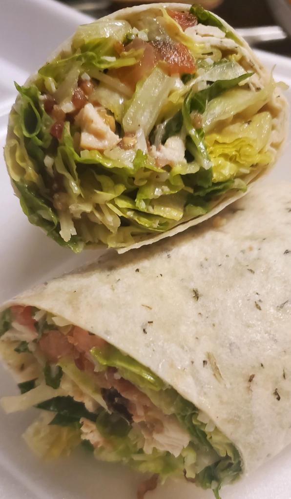 Chicken Caesar Wrap · Tender chicken breast with crisp romaine lettuce, caesar dressing ,parmesan cheese , bacon and tomato wrapped in a warm garlic herb tortilla. Served with fries.
