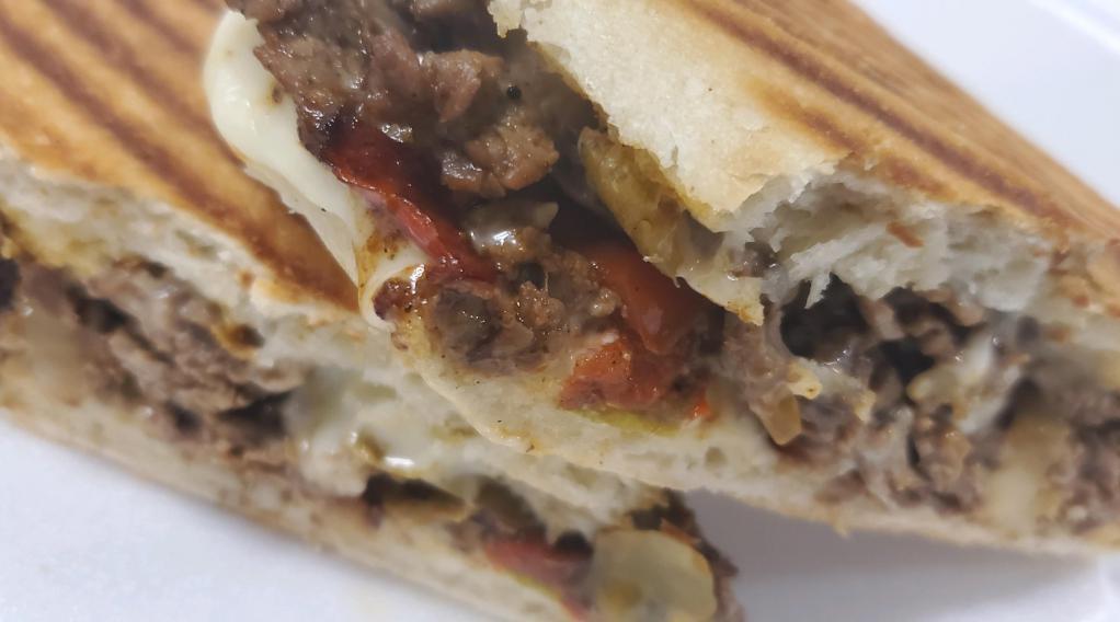 Cajun Steak and Cheese Panini · Shaved top round steak mixed with cajun and tabasco seasoning and then mixed with onions, peppers and mushrooms and smothered with American cheese and then sandwiched between ciabatta bread. Served with fries.