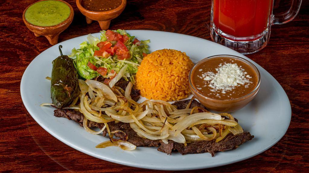 Bistec a la Mexicana · Chopped steak with bell peppers and onions with a side salad.