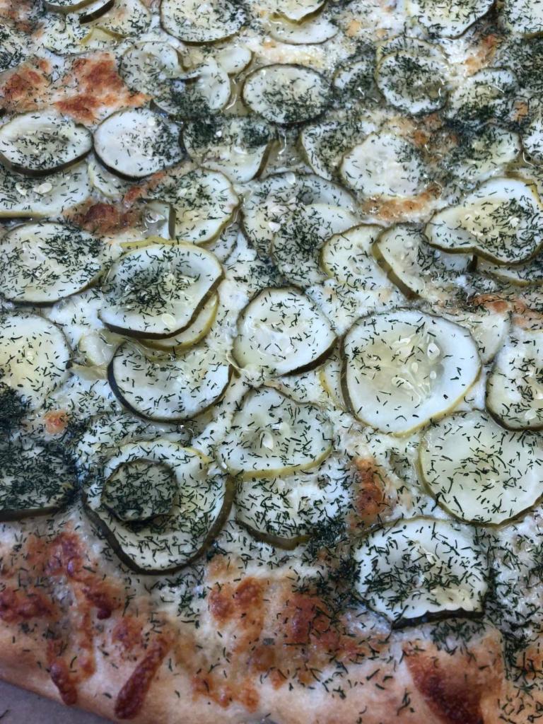 Dill Pickle Pizza Rhino's · White garlic pizza with mozzarella cheese topped with dill pickle slices and dill weed sprinkle,