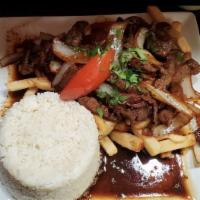 Lomo Saltado · Tender beef saute with onions, tomatoes in a soy sauce. Served with French fries, and white ...