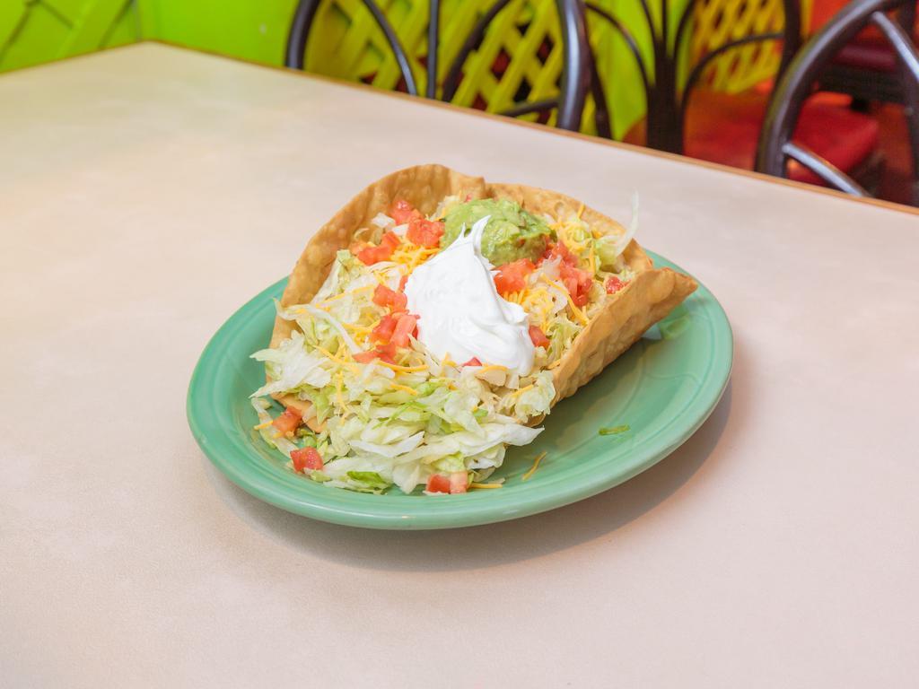 Chicken Taco Salad · Fresh meat topped with cheese and heated until the cheese is simmering, then topped again with lettuce, cheese, and tomatoes. Served in a crispy flour tortilla with guacamole and sour cream.