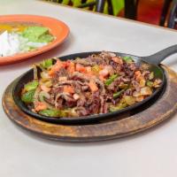 Steak Las Fajita · Beef marinated in secret sauce then served sizzling hot over a bed of sautéed onions and gre...