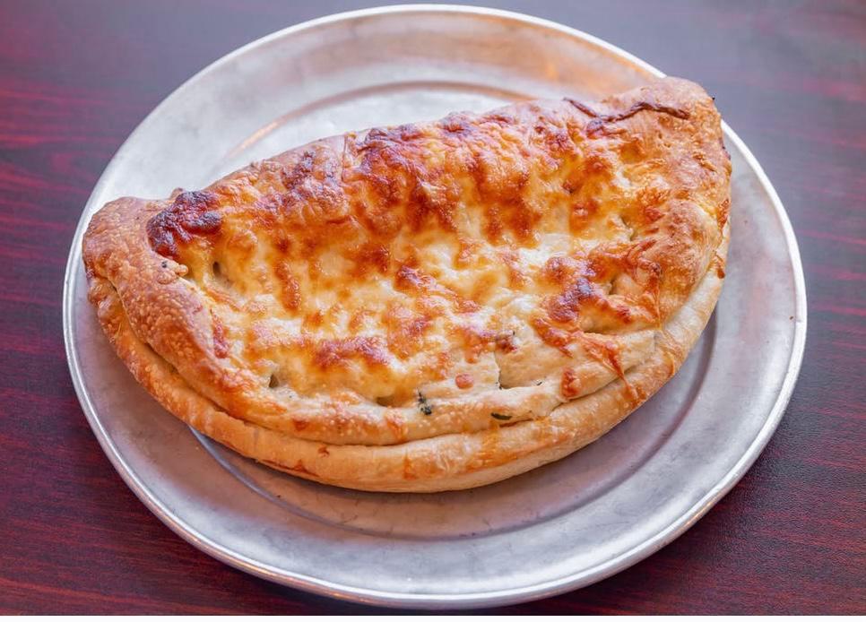Tony's Calzone · Made with our homemade dough, folded over and stuffed with fresh ingredients (pizza cheese, roast beef, pastrami, ham and sliced banana peppers), sprinkled with blended cheeses and oven baked.