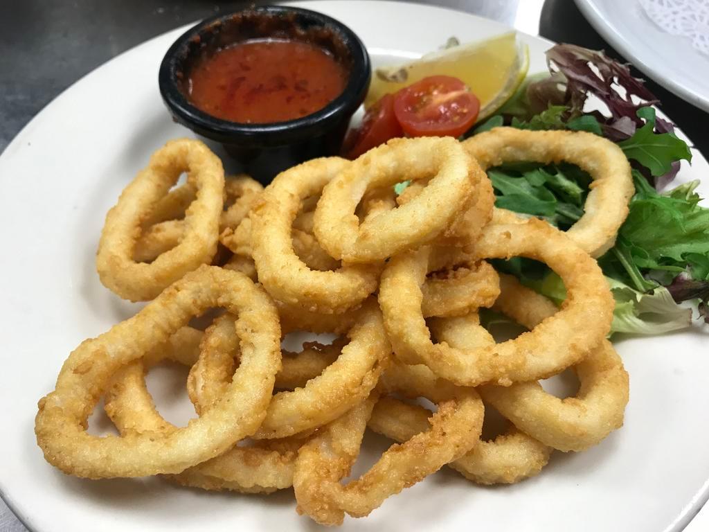 Calamari Fritti Rings · Deep fried breaded calamari served with marinara sauce and a lemon wedge, garnished with green leaf lettuce and tomato.