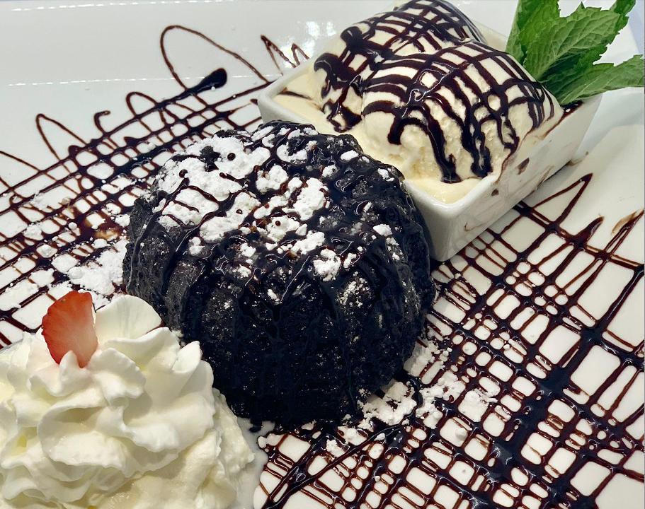 Lava Cake · Our moist dark chocolate cake enrobed with dark chocolate... filled with a dark chocolate truffle that melts out. Served with vanilla ice creem and drizzled with chocolate sauce.